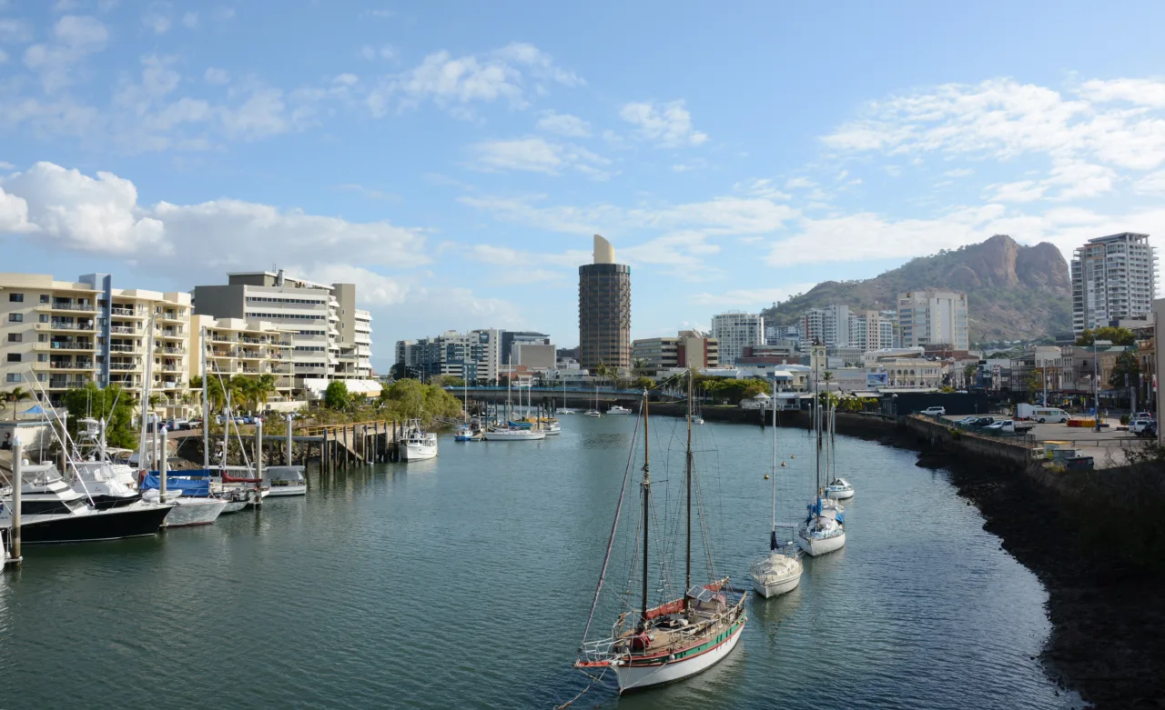 Ross River flowing through Townsville CBD with the Castle Hill in the background. The building seen in the middle of the picture is the iconic "Sugar Shaker", it is now Hotel Grand Chancellor. The ship seen in the front is the historic Defender, which sank in January 2016 at the same location.